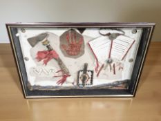 A glazed montage containing reproduction Native America tomahawk, knife, and similar articles,