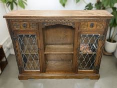 An Old Charm carved oak bookcase with leaded glass doors, 123 cm x 29 cm x 100 cm.