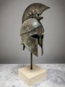 A bronze replica of an Ancient Greek hoplite battle helmet, on square marble plinth, height 43 cm.