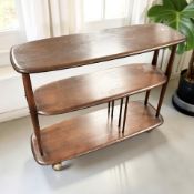 An Ercol stained elm three tier bookcase on shepherd's castors, 90 cm x 32 cm x 72 cm.