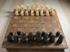 A carved resin chess board with chess set