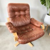 A Scandinavian laminated and terracotta leather swivel armchair