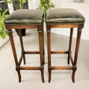 A pair of reproduction stools in studded green leather, width 32 cm.