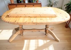 A contemporary pine oval extending table with two leaves,