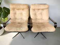 A pair of Scandinavian chairs with tan leather cushions