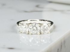 An 18ct white gold three stone diamond ring, the brilliant-cut stones in raised claw settings,