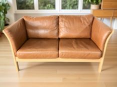 A contemporary Danish wooden framed tan leather two seater settee,