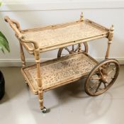 An eastern heavily carved hardwood and brass inlaid drinks trolley, length 92 cm.