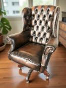 A contemporary Chesterfield deep button tan leather wing back swivel armchair,