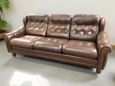 A Scandinavian three seater settee in deep buttoned brown leather,