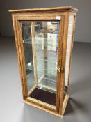 A glazed oak counter top display cabinet with glass shelved interior, 38 cm x 26 cm x 77 cm.
