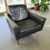 A Scandinavian black leather lounge chair on teak legs,