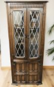 A reproduction oak and leaded glass double door corner cabinet, height 167 cm.