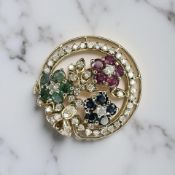 An 18ct gold brooch set with diamonds, rubies, sapphires, and emeralds, diameter 2.