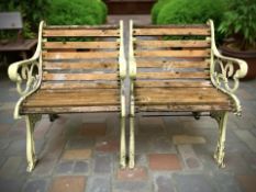 A pair of painted cast iron-framed garden armchairs, each 63 cm wide.