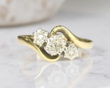 An 18ct yellow gold three stone diamond cross-over ring, size N/O.