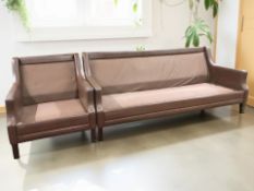 A Scandinavian brown leather three seater settee matching armchair (lacking cushions)