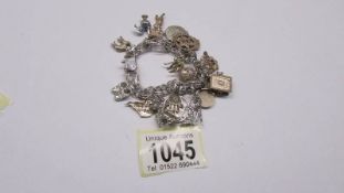 A silver charm bracelet with numerous silver and white metal charms.