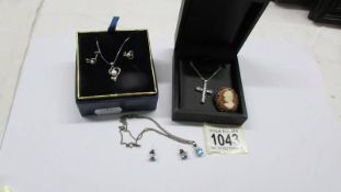 Two silver pendants with matching earrings, a silver cross on chain and a cameo brooch.