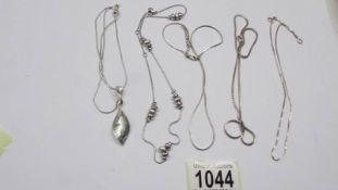 Three silver chains, a silver necklace and a silver leaf pendant.