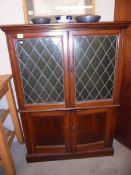 An Edwardian two door lead glazed cabinet with green glass doors.