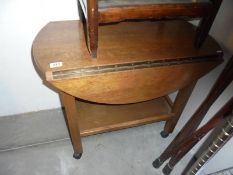 An Edwardian oak drop leaf tea trolley.