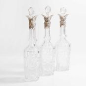 A set of three silver-mounted cut-glass decanters,