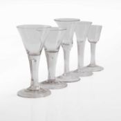 A group of five plain stem wine glasses,