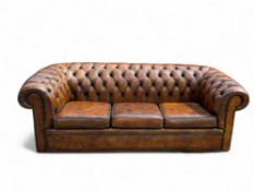 A vintage brown leather upholstered chesterfield three-seater sofa
