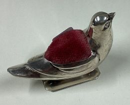 A silver pin cushion in the form of a bird.