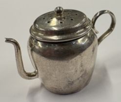 A silver tea infuser in the form of a teapot.