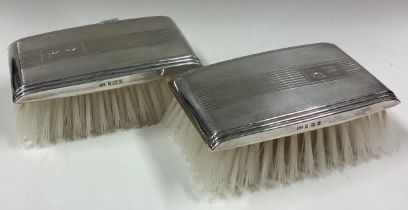 A pair of engine turned silver-mounted hairbrushes.