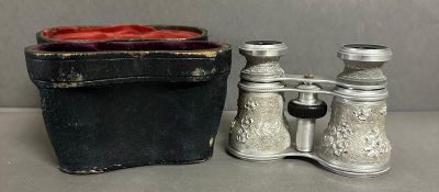 A pair of cased opera glasses with an ornate white metal floral relief case AF