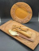 A wooden carved plate along with serving utensils