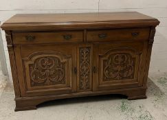 An oak sideboard with two drawers and two carved panel doors below (H97cm W150cm D54cm)