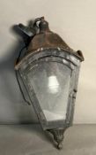 A wall lantern with metal frame and glass panels