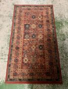 A red ground rug with blue boarder 153cm x 80cm