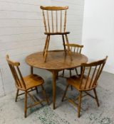 A circular extendable dining table and four spindle back chairs (H72cm Dia110cm)