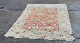A large wool rug, red grounds with a floral pattern and floral geometric boarder (410cm x 307cm)