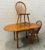 A pine extendable kitchen table and two stick back chairs (H76cm W138cm D78cm)