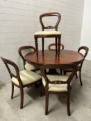 A mahogany circular dining table on a heavily carved pedestal base and splayed scrolling legs and