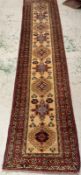 A wool runner, red grounds and with a geometric border (301cm x 72cm)