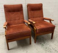 A pair of Mid Century arm chairs with button backs and upholstered in a burgundy fabric