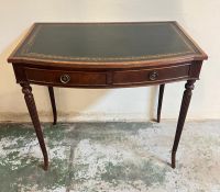 A bow-front side table with a green leather inlaid top, raised on tapering fluted legs with