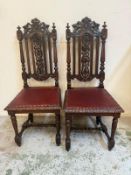 A pair of mahogany hall chairs with heavily carved backs, red leather seats and turned fluted legs