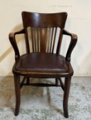 An Edwardian oak desk chair with brown leather seat