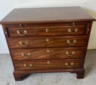 A small chest of drawers with a pull-out tray, raised on bracket feet. (H78cm W85cm D46cm)