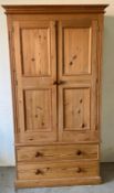 A double pine wardrobe with panelled doors and a double drawer beneath. (H198cm W104cm D55cm)