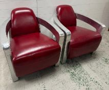 A pair of red aviator chairs, with riveted aluminium panels and padded leather upholstery.