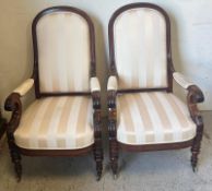 A pair of upholstered elbow chairs, each with scrolling arms, carved feet, and moulded show-wood